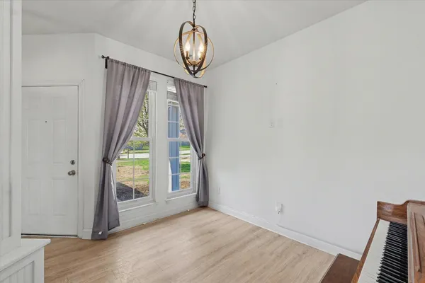an empty room with wooden floor mirror and windows
