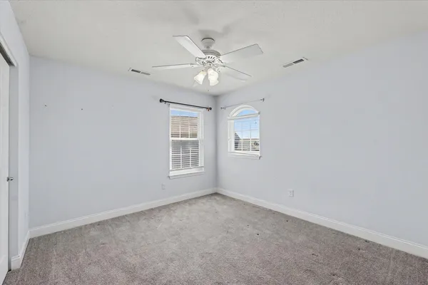 an empty room with a window and a fan