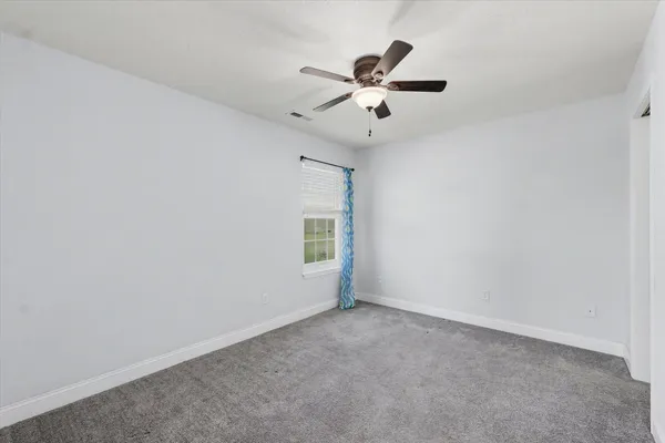 an empty room with a window and a fan