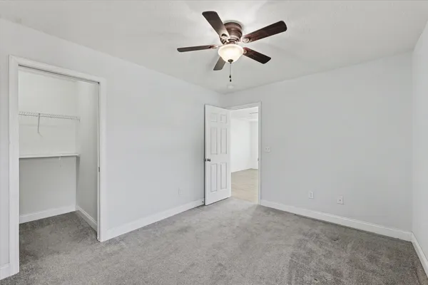 an empty room with a ceiling fan and a window