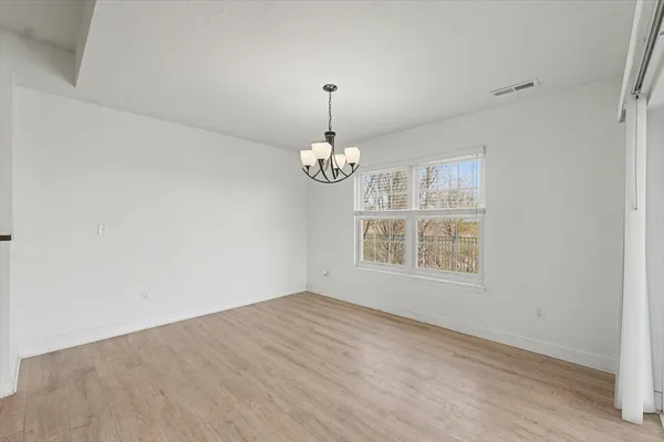 an empty room with chandelier fan and windows