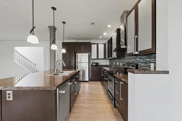 a kitchen with stainless steel appliances granite countertop a sink a stove and a wooden floors