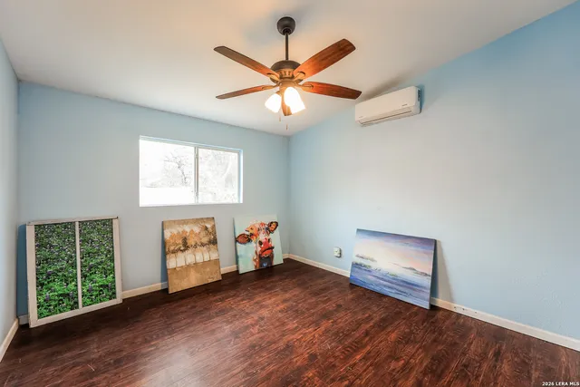 an empty room with wooden floor fan and windows