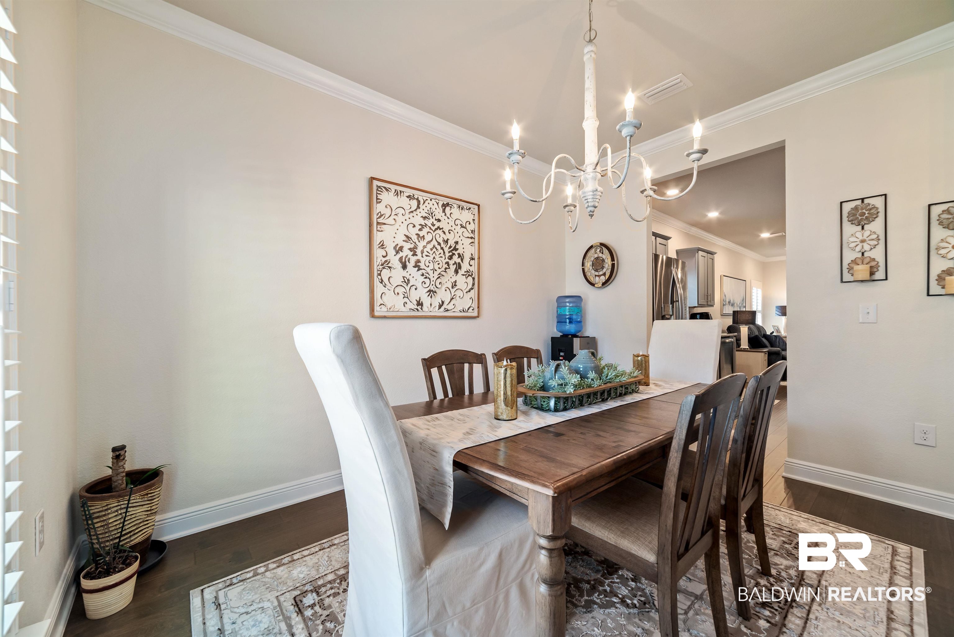 1290 Mako Loop Gulf Shores, AL 36542 - Photo 4 of 50 Dining room with baseboards, dark wood-style flooring, visible vents, and crown molding