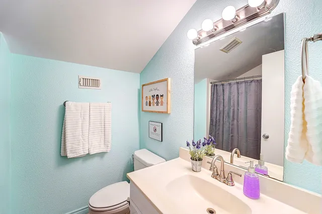 a bathroom with a sink vanity mirror and toilet