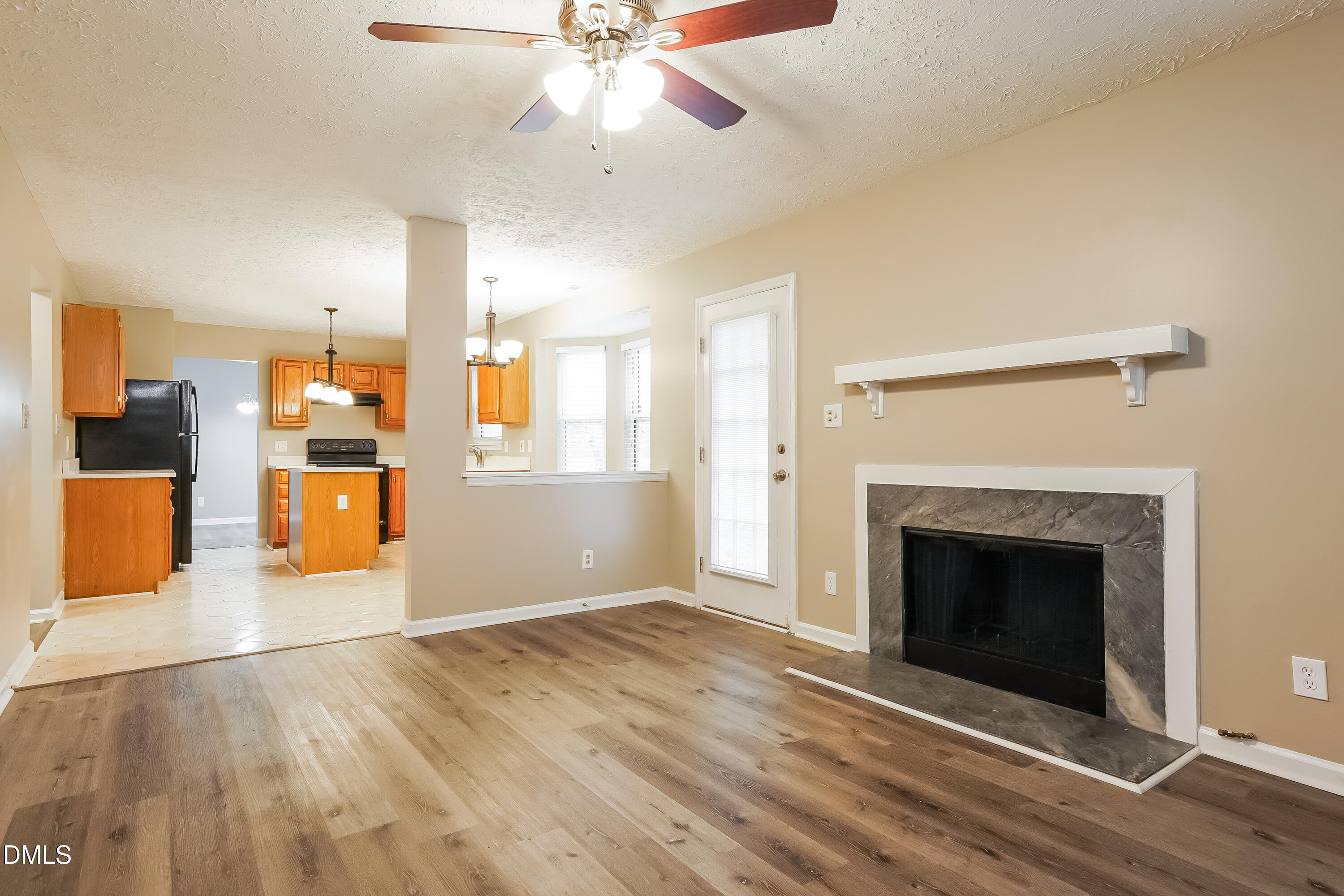 1132 Penselwood Drive Raleigh, NC 27604 - Photo 2 of 17 an empty room with wooden floor a ceiling fan a fireplace and windows