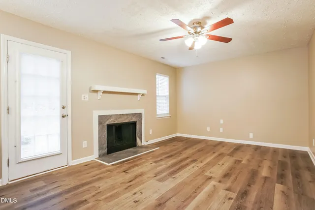 a view of an empty room with wooden floor and a fireplace