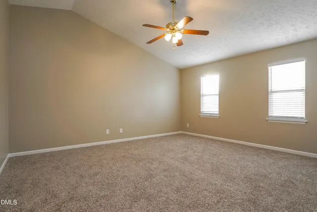 an empty room with windows and chandelier fan