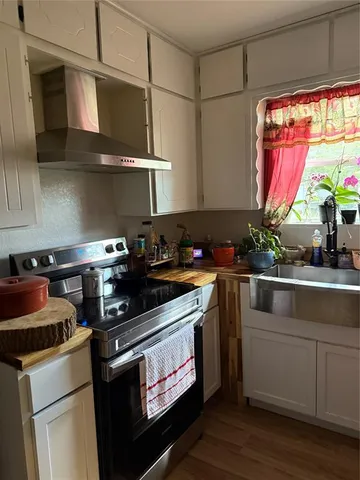 a kitchen with stainless steel appliances granite countertop a stove a sink and white cabinets