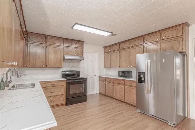 a kitchen with granite countertop a refrigerator stove and sink
