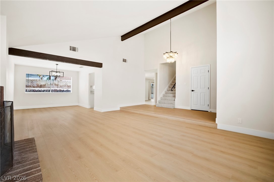 2411 Doherty Way Henderson, NV 89014 - Photo 5 of 34 A spacious, naturally illuminated living room featuring a grand fireplace, vaulted ceilings, and a striking chandelier.