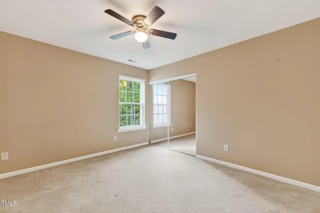 an empty room with windows and fan