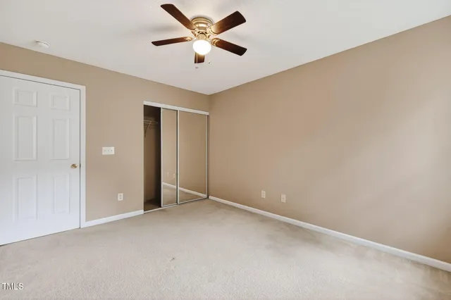 an empty room with closet and fan