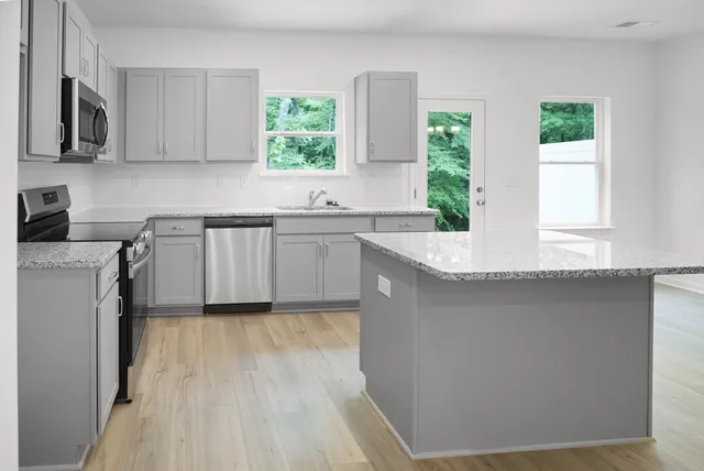 a kitchen with a sink cabinets stainless steel appliances and a window