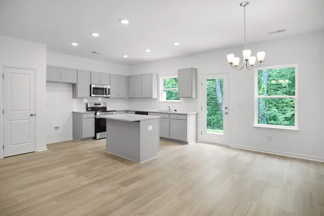 a kitchen with stainless steel appliances granite countertop a sink a stove a refrigerator and island with wooden floor