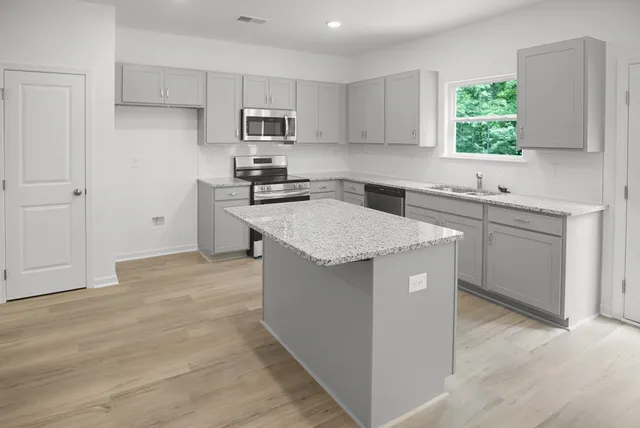 a kitchen with stainless steel appliances granite countertop a stove a sink a microwave and a refrigerator