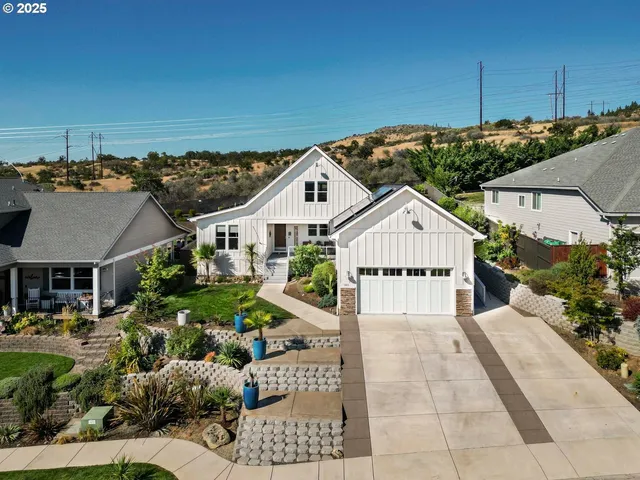 a view of a white house next to a yard with potted plants