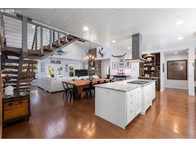 a living room with stainless steel appliances kitchen island granite countertop a stove and a wooden floors