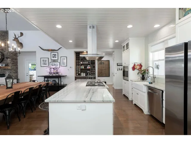 a kitchen with stainless steel appliances kitchen island granite countertop a stove a sink dishwasher and a refrigerator with wooden floor