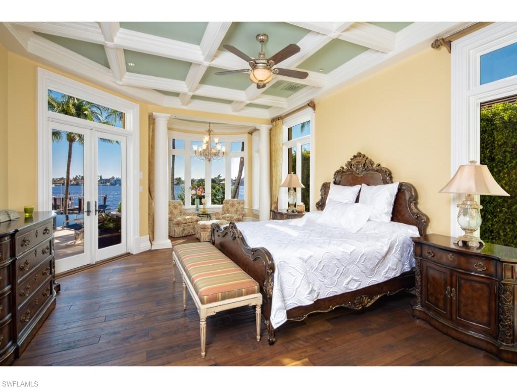 980 Aqua Circle Naples, FL 34102 - Photo 9 of 19 a spacious bedroom with a bed a table and large windows