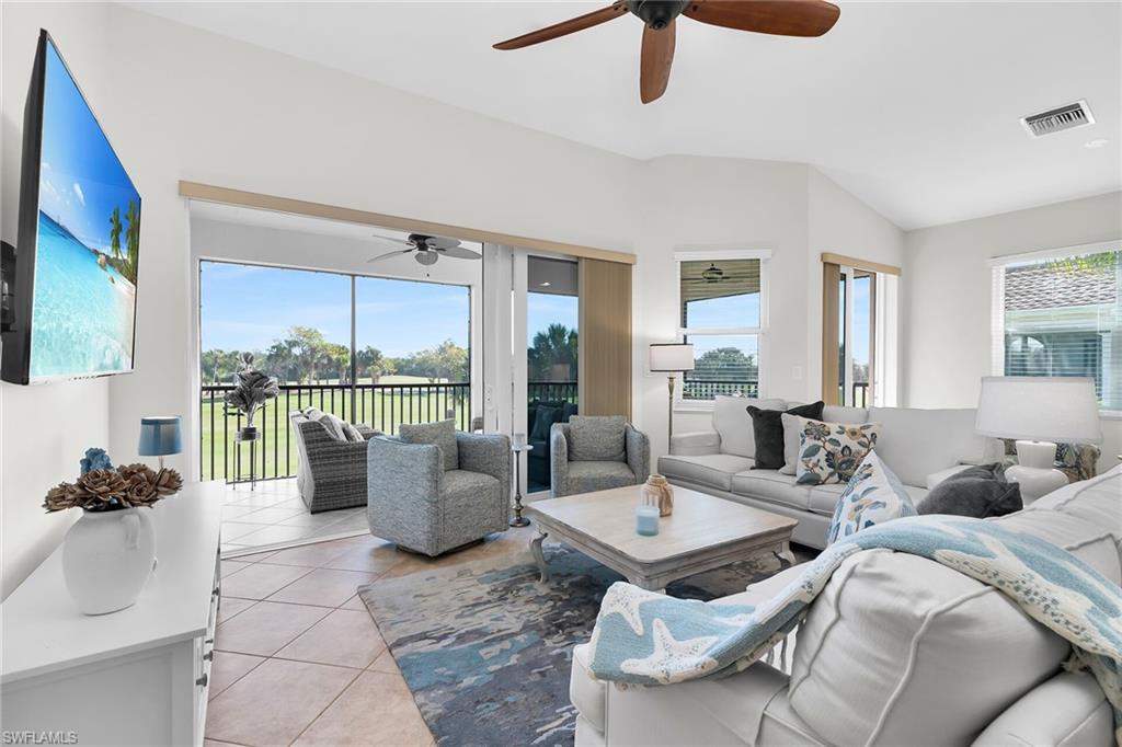 1286 Rialto Way, Unit 9202 Naples, FL 34114 - Photo 15 of 49 Spacious living area featuring vaulted ceilings, neutral finishes, ceiling fan, and sliding glass doors opening to the lanai with peaceful views.