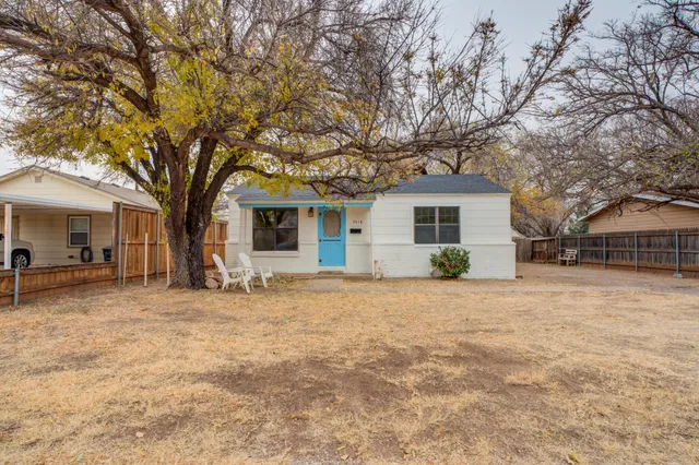 a front view of house with yard and trees in the background