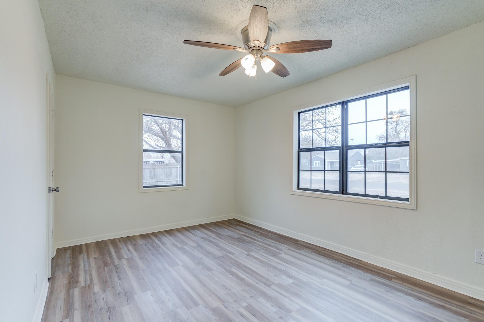 3318 36th Street Lubbock, TX 79413 - Photo 14 of 22 an empty room with wooden floor chandelier fan and windows