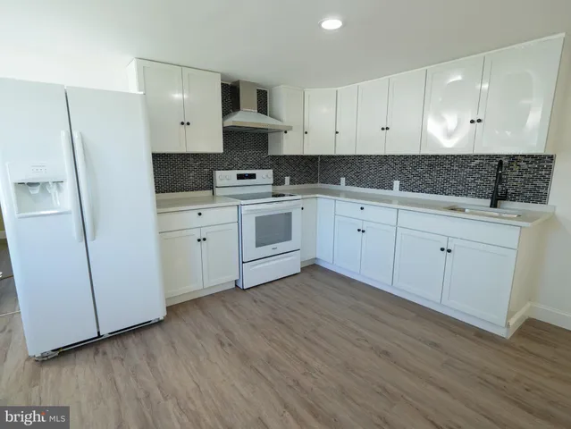 a kitchen with cabinets appliances and a wooden floor