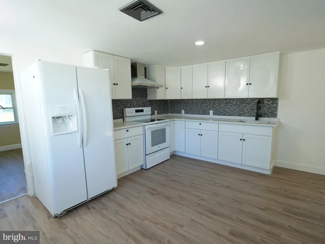 a kitchen with stainless steel appliances a sink cabinets and wooden floor