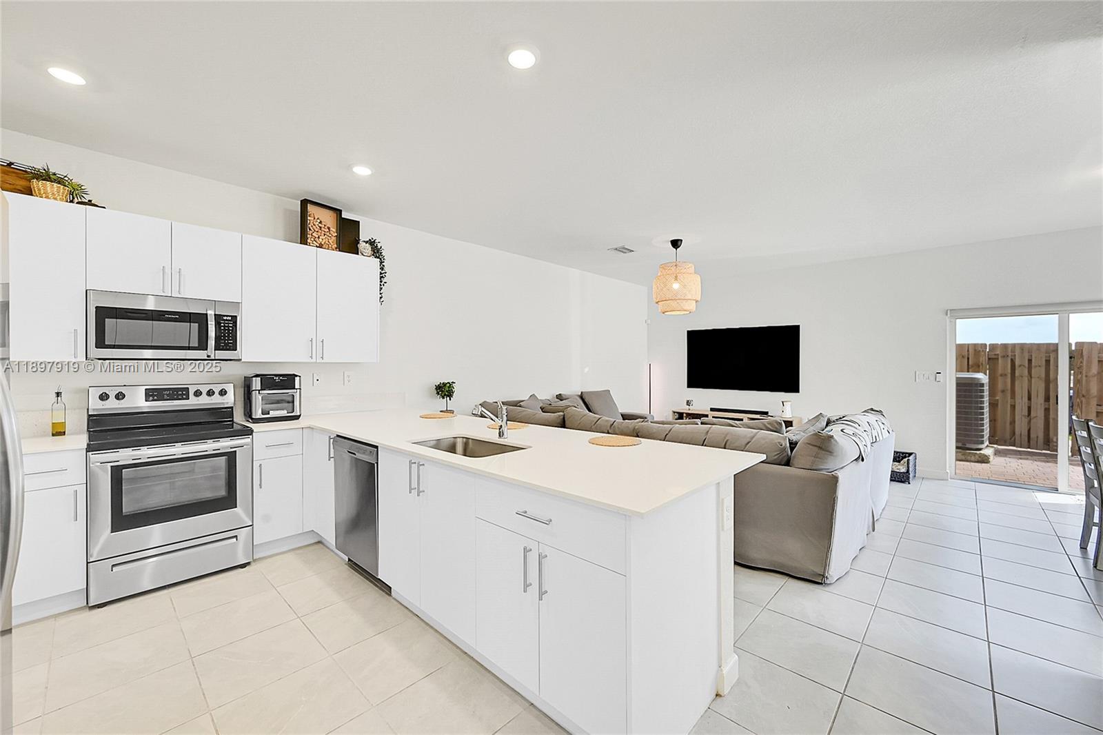 14832 Southwest 265th Street Homestead, FL 33032 - Photo 9 of 43 a large white kitchen with a stove top oven and a sink