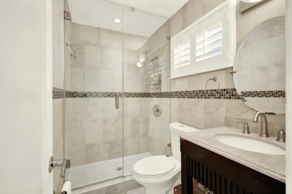 a bathroom with a granite countertop sink a toilet and shower
