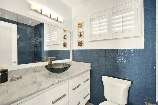 a bathroom with a granite countertop toilet sink and mirror