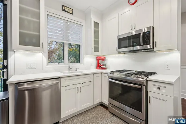 a kitchen with stainless steel appliances white cabinets white stove a microwave and a refrigerator