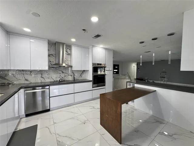 a large kitchen with kitchen island a sink stainless steel appliances and cabinets