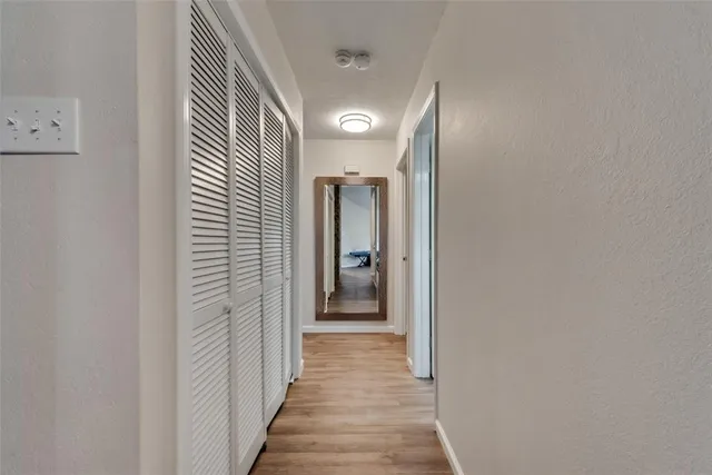 a view of a hallway with wooden floor and closet