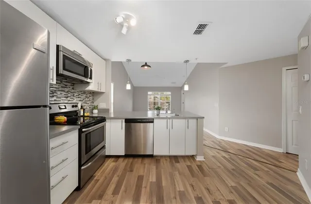a view of kitchen with stainless steel appliances granite countertop a refrigerator and a stove top oven