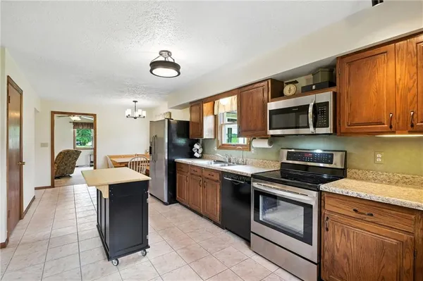 a kitchen with stainless steel appliances granite countertop a stove top oven a sink dishwasher a dining table and chairs with wooden floor