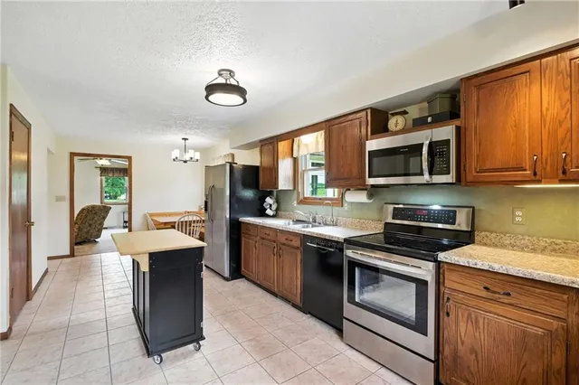 a kitchen with stainless steel appliances granite countertop a stove top oven a sink dishwasher a dining table and chairs with wooden floor