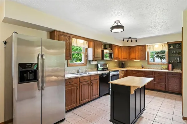 a kitchen with stainless steel appliances granite countertop a stove a sink a refrigerator and island
