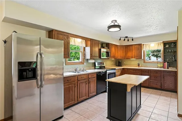 a kitchen with stainless steel appliances granite countertop a stove a sink a refrigerator and island