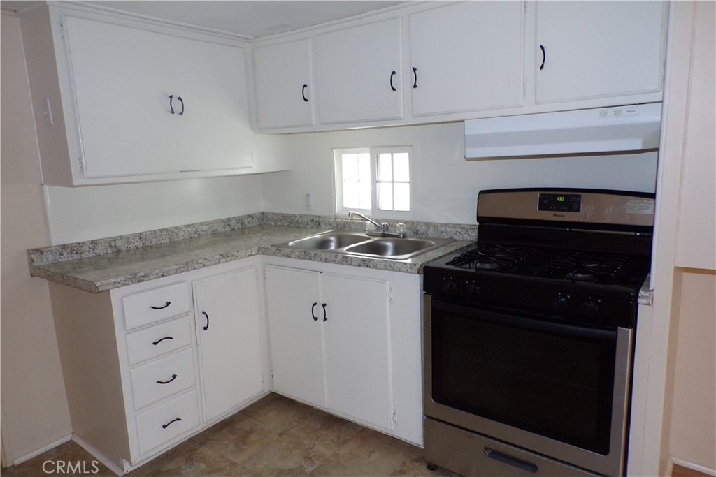 12710 3rd Street, Unit 57 Yucaipa, CA 92399 - Photo 8 of 13 a kitchen with granite countertop white cabinets and black appliances