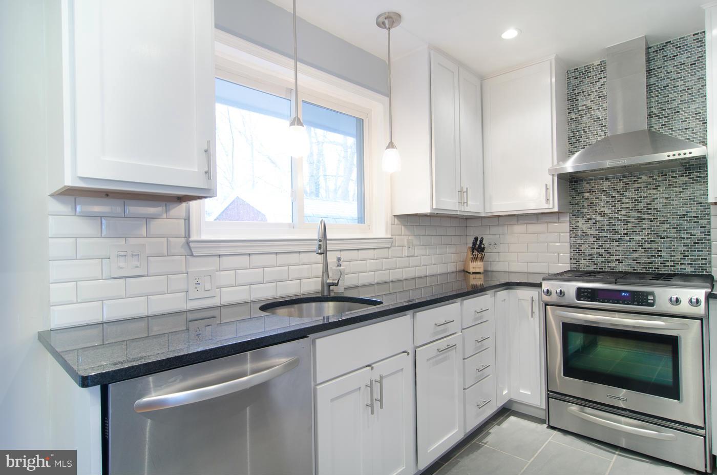 a kitchen with granite countertop a sink stainless steel appliances white cabinets and a window