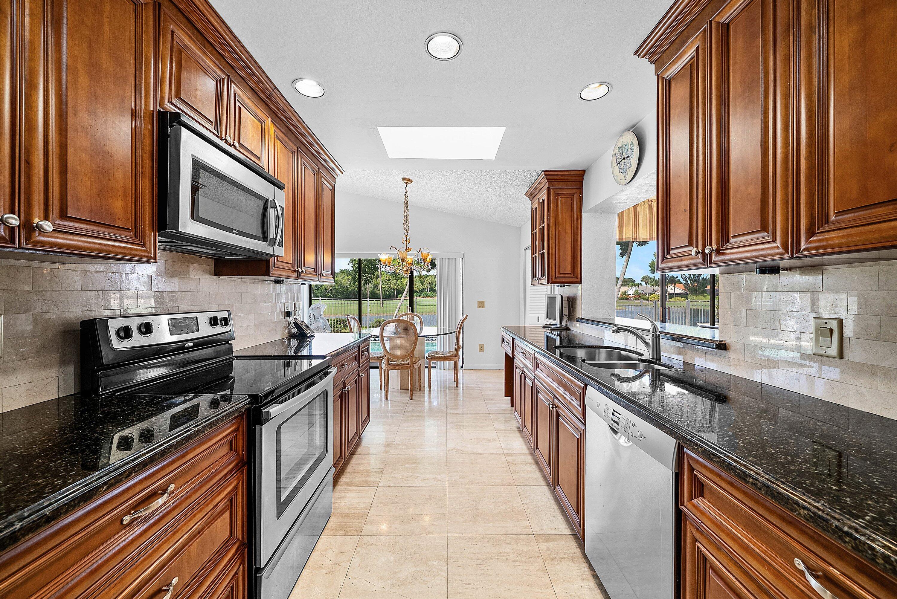 21459 Bridgeview Drive Boca Raton, FL 33428 - Photo 13 of 61 a kitchen with stainless steel appliances granite countertop a stove top oven a sink dishwasher a dining table and chairs with wooden floor