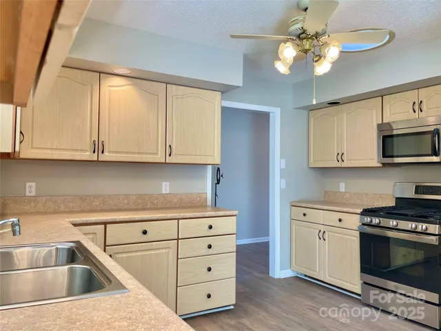 a kitchen with cabinets appliances a sink and a window