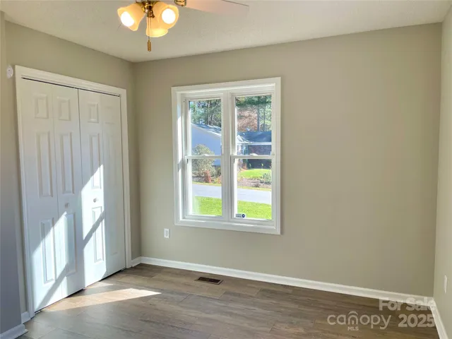 a view of an empty room with wooden floor and a window