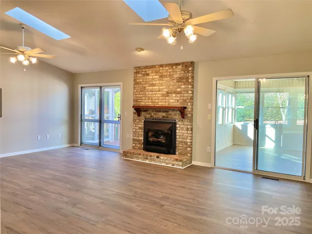 an empty room with wooden floor fireplace and chandelier