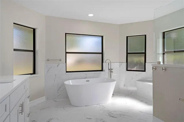 an empty room with wooden floor ceiling fan and windows