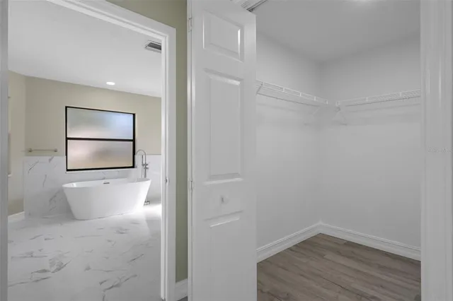 an empty room with wooden floor chandelier and windows