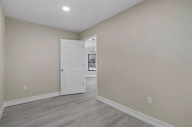 a kitchen with stainless steel appliances granite countertop a stove a sink and white cabinets with wooden floor next to windows