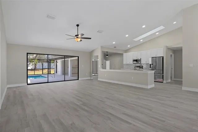 a view of an empty room with window and wooden floor
